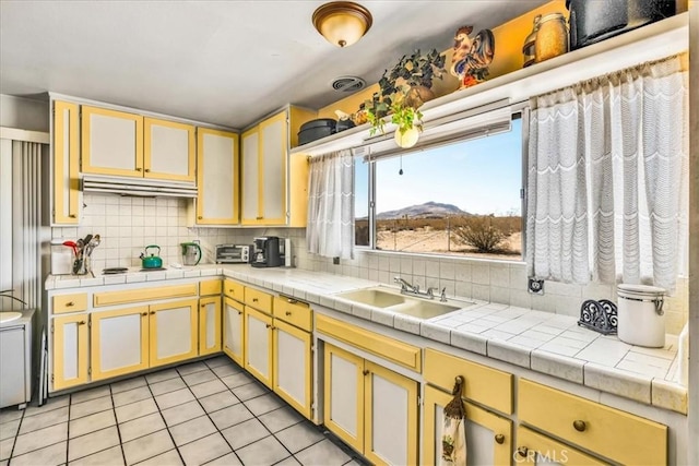 kitchen with tile counters, a mountain view, sink, and decorative backsplash