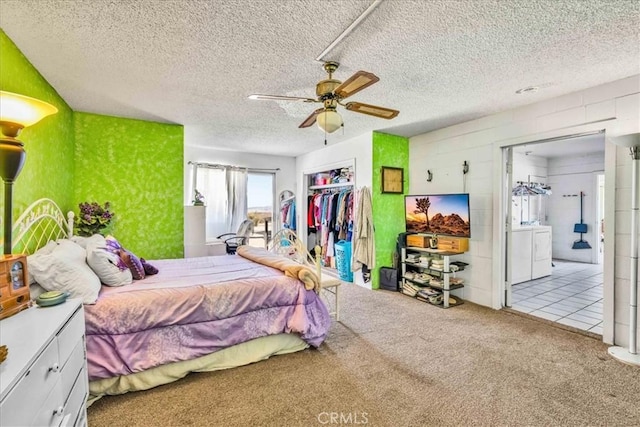 carpeted bedroom featuring ensuite bathroom, ceiling fan, washing machine and dryer, a textured ceiling, and a closet