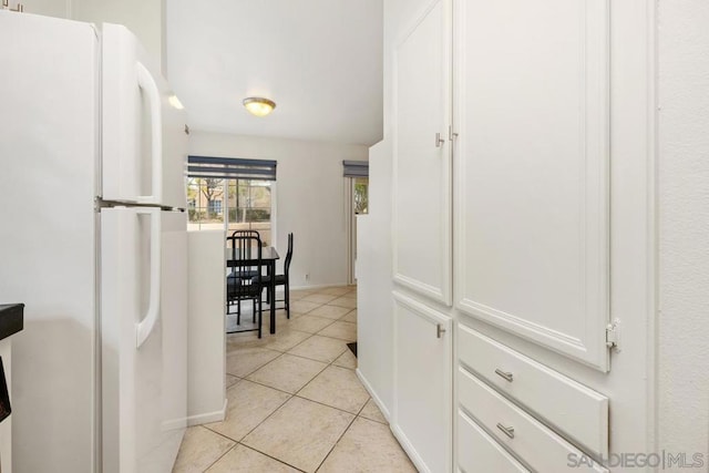 kitchen featuring white refrigerator, light tile patterned floors, and white cabinets