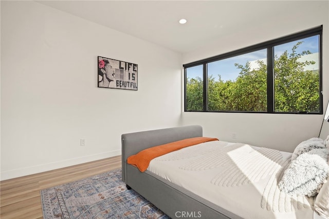 bedroom with recessed lighting, wood finished floors, and baseboards