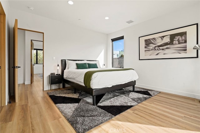 bedroom with visible vents, light wood-style flooring, and multiple windows