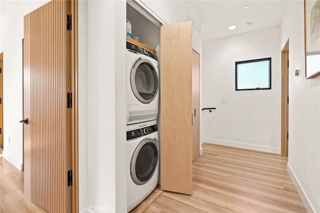 washroom featuring stacked washer and clothes dryer, recessed lighting, light wood-type flooring, laundry area, and baseboards