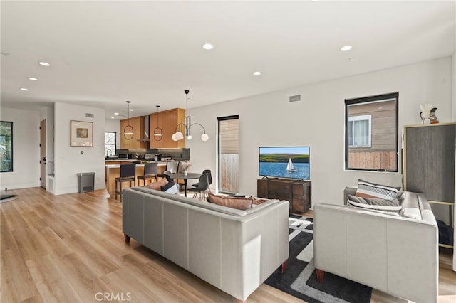 living area with light wood-type flooring, baseboards, visible vents, and recessed lighting