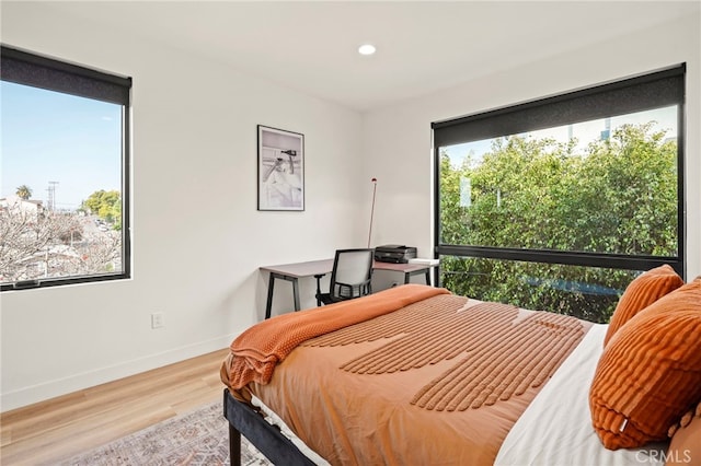 bedroom featuring multiple windows, baseboards, wood finished floors, and recessed lighting