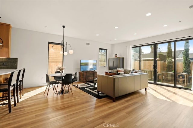 living area with recessed lighting, visible vents, and light wood finished floors