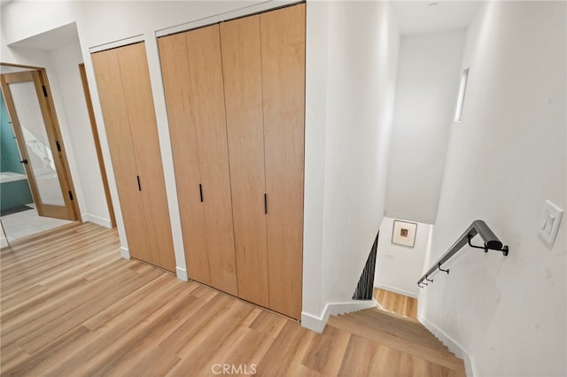 interior space featuring baseboards, radiator, light wood finished floors, and multiple closets