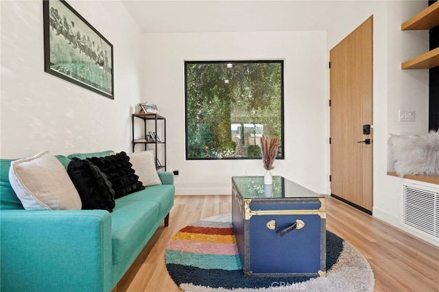 living room featuring light wood-style flooring, visible vents, and baseboards