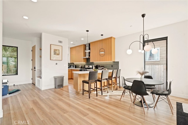 kitchen with light brown cabinets, visible vents, appliances with stainless steel finishes, light wood-type flooring, and tasteful backsplash