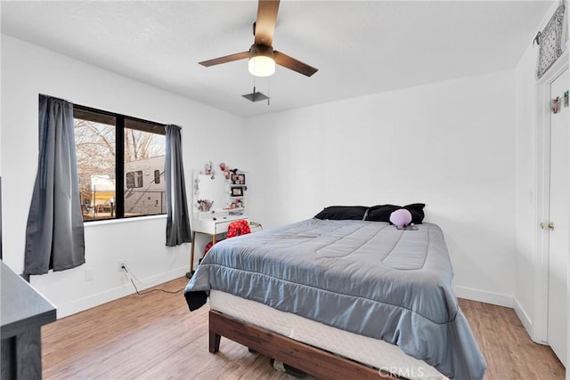 bedroom featuring light wood-type flooring, a ceiling fan, and baseboards