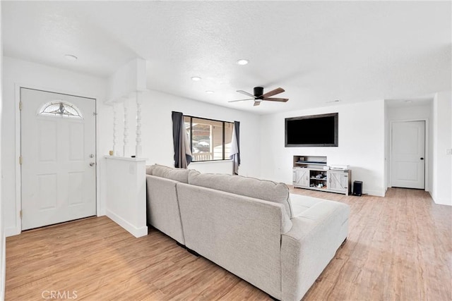 living area with light wood-style flooring, a textured ceiling, baseboards, and a ceiling fan