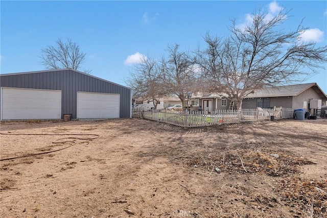 view of yard featuring a garage, fence, and an outbuilding