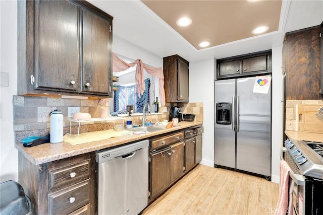 kitchen with light wood-style flooring, appliances with stainless steel finishes, tasteful backsplash, and dark brown cabinets