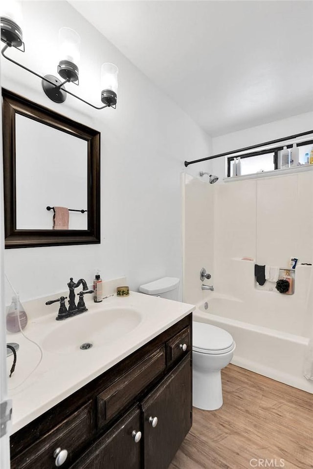 full bathroom with toilet, shower / bathing tub combination, wood finished floors, and vanity