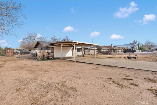 back of house featuring a carport, fence, and concrete driveway