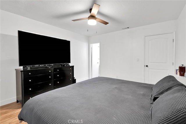 bedroom with light wood finished floors, baseboards, visible vents, and a ceiling fan