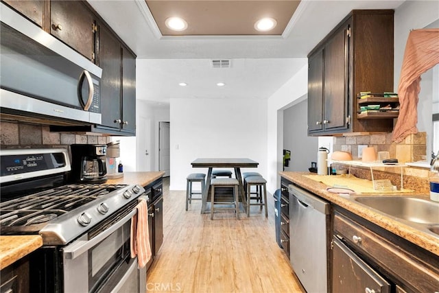 kitchen with visible vents, appliances with stainless steel finishes, a tray ceiling, light countertops, and light wood-style floors