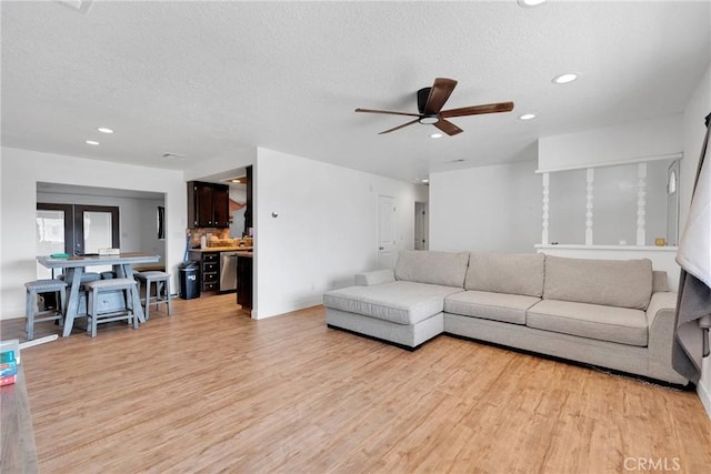 living area with light wood-style floors, a ceiling fan, a textured ceiling, and recessed lighting