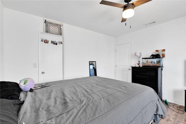 bedroom with light wood finished floors, ceiling fan, and visible vents