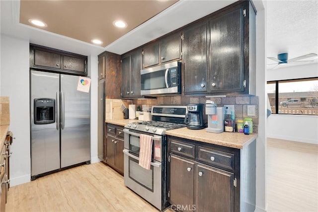 kitchen with appliances with stainless steel finishes, light wood-type flooring, light countertops, and backsplash