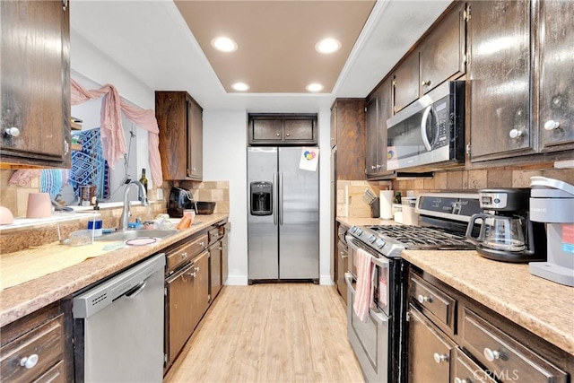 kitchen with decorative backsplash, a raised ceiling, appliances with stainless steel finishes, light countertops, and a sink