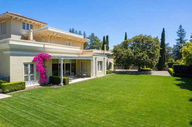 back of property featuring a lawn and a patio area