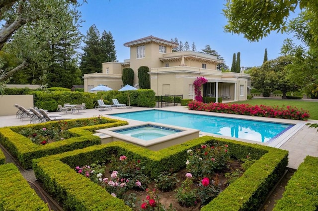 rear view of property with a patio and a pool with hot tub