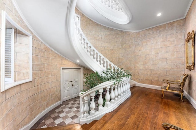 stairway with hardwood / wood-style flooring, ornamental molding, and vaulted ceiling