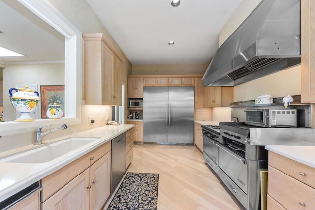 kitchen with wall chimney range hood, sink, light hardwood / wood-style flooring, stainless steel appliances, and light brown cabinets