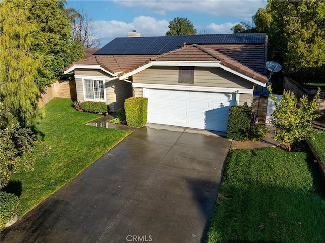 view of front facade featuring a garage, a front yard, and solar panels