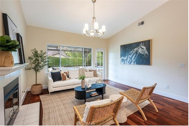 living room with vaulted ceiling, light wood-type flooring, a chandelier, and a fireplace