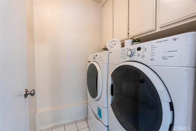 clothes washing area featuring cabinets, washing machine and dryer, and light tile patterned flooring