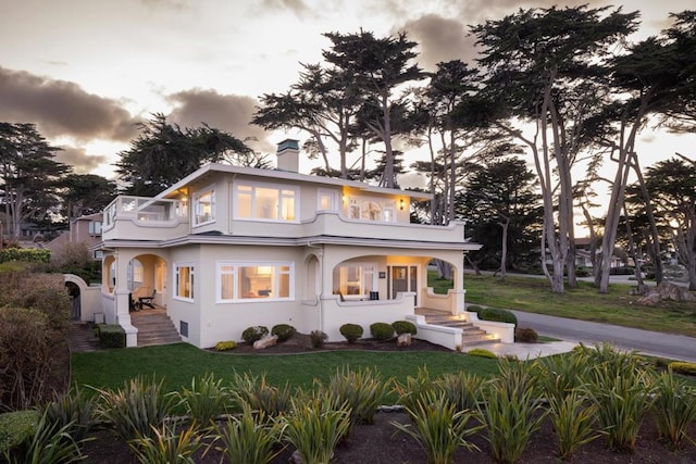 view of front facade featuring a porch, a yard, and a balcony