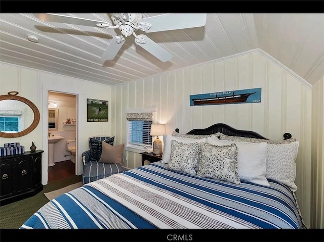 bedroom with ensuite bath, vaulted ceiling, and dark colored carpet