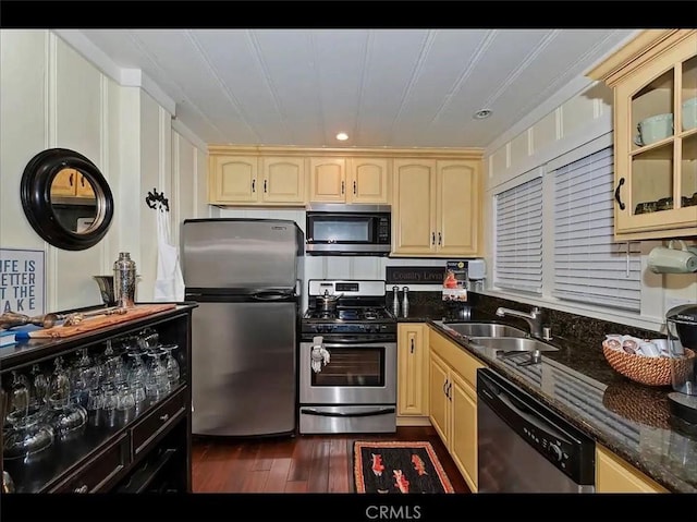 kitchen featuring appliances with stainless steel finishes, dark hardwood / wood-style flooring, sink, and dark stone counters