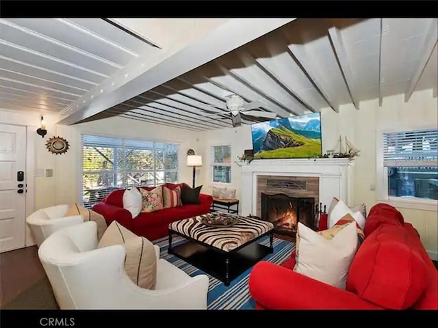 living room featuring beamed ceiling, a premium fireplace, and ceiling fan