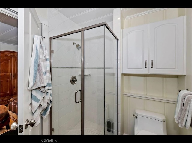 bathroom featuring ornamental molding, toilet, and a shower with door