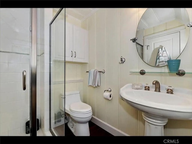 bathroom featuring a shower with door and toilet