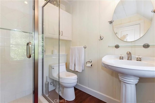 bathroom featuring an enclosed shower, sink, hardwood / wood-style flooring, and toilet