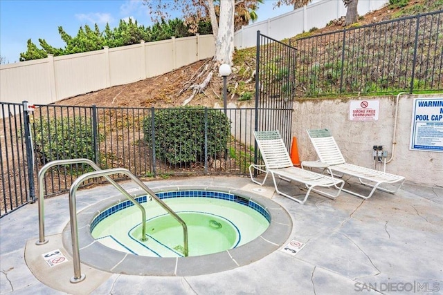 view of swimming pool featuring a hot tub and a patio area