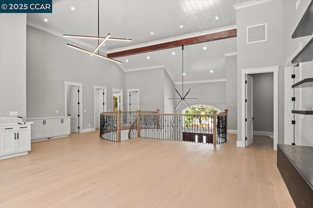 interior space featuring crown molding, light wood-type flooring, a notable chandelier, and high vaulted ceiling