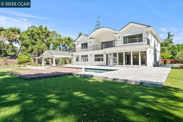 rear view of house featuring a fenced in pool, a patio, a balcony, and a yard