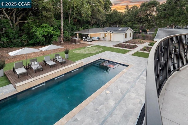 pool at dusk featuring an outbuilding, pool water feature, and a patio