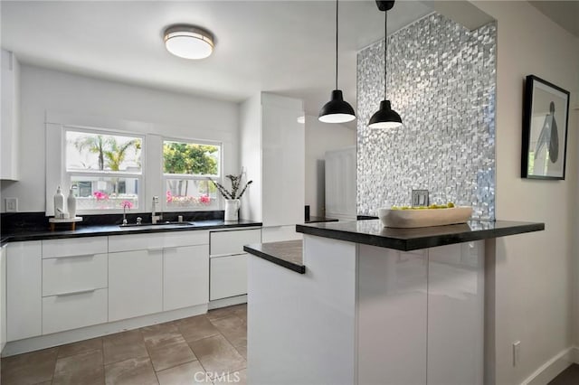 kitchen with light tile patterned floors, sink, white cabinets, decorative light fixtures, and kitchen peninsula