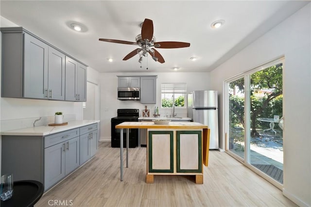 kitchen with gray cabinets, appliances with stainless steel finishes, wood counters, sink, and light wood-type flooring