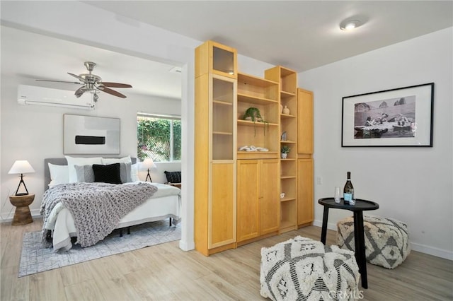 bedroom with a wall mounted air conditioner and light hardwood / wood-style floors