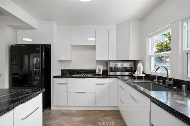 kitchen with sink, white cabinets, dark stone counters, and black appliances