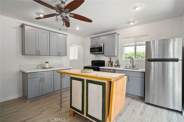 kitchen with gray cabinets, appliances with stainless steel finishes, sink, wooden counters, and light hardwood / wood-style floors