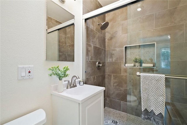 bathroom featuring vanity, an enclosed shower, and toilet