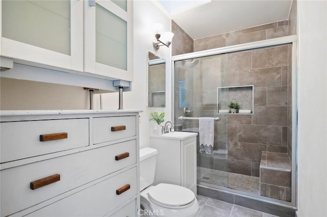 bathroom with walk in shower, vanity, tile patterned floors, and toilet