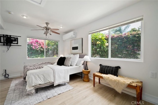 bedroom with ceiling fan, a wall mounted AC, and light wood-type flooring